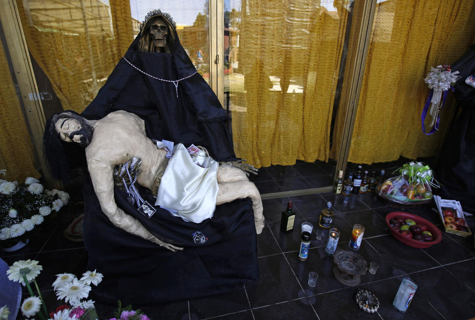 FILE - In this March 1, 2017 file photo, a statue of La Santa Muerte, or "Our Lady of Holy Death," holds a statue of Jesus on an altar inside a temple dedicated to Santa Muerte, on the outskirts Mexico City in the State of Mexico. Santa Fe Archbishop John Wester in Albuquerque, New Mexico, recently told The Associated Press he believes some Catholics may be fooled into venerating Santa Muerte even though the focus on death runs counter to the church's teachings and she's not an official Catholic saint. (AP Photo/Marco Ugarte, File)