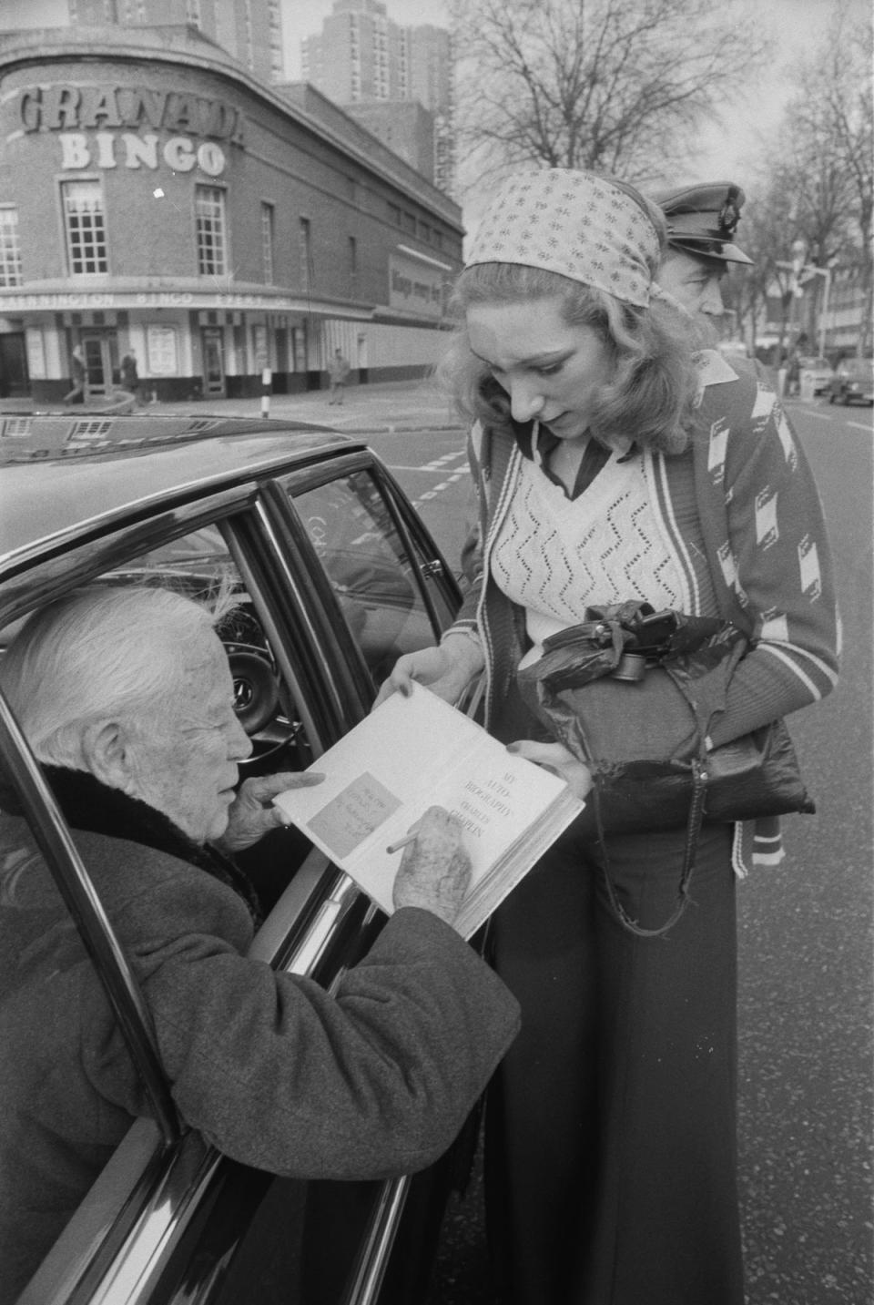 Charlie Chaplin signs a copy of his autobiography for a fan on 13 January 1975 (Evening Standard/Hulton Archive/Getty Images)