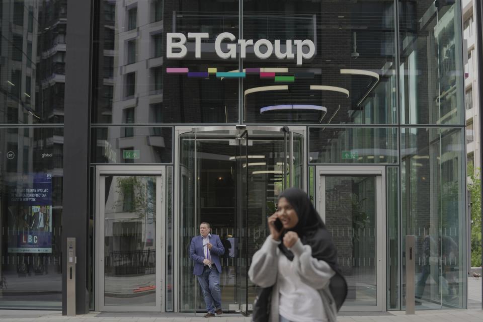 People walk in front of the BT headquarters, in London, Thursday, May 18, 2023. U.K. telecom company BT Group said Thursday that it plans to shed up to 55,000 jobs by the end of the decade as part of an overhaul aimed at slimming down its workforce to slash costs. (AP Photo/Kin Cheung)