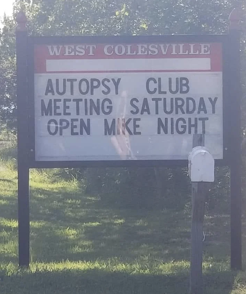 Sign reads "WEST COLESVILLE AUTOPSY CLUB MEETING SATURDAY OPEN MIKE NIGHT."