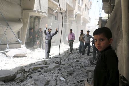 Residents react as they stand upon the rubble of collapsed buildings after what activists said was shelling by forces loyal to Syria's President Bashar al-Assad at Ain Tarma in eastern Ghouta, a suburb of Damascus, Syria April 26, 2015. REUTERS/Amer Almohibany