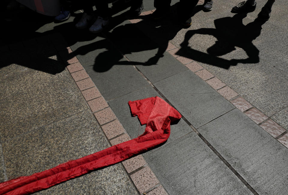 The shadows of protesters are seen next to a red ribbon symbolizes the bottom line of the Chinese Communist Party during a protest in Hong Kong, Saturday, Oct. 6, 2018. The protesters staged a rally against Hong Kong's government has refused to renew the work visa of Victor Mallet, a senior editor of the Financial Times, in what human rights activists say is the latest sign of a deteriorating human rights situation in the semi-autonomous Chinese territory. (AP Photo/Vincent Yu)