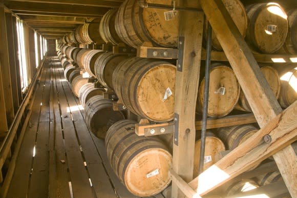 A line of whiskey barrels stacked on three shelves