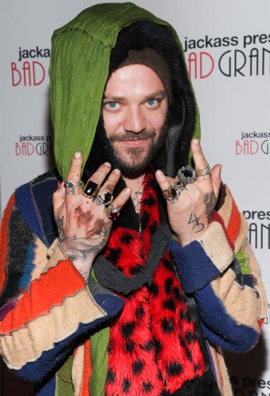 Bam Margera poses in layers of clothing and holds up his hands with many rings
