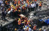 Rescue workers use a stretcher to carry a woman who was rescued from the rubble at the site of a collapsed residential building in Mumbai September 27, 2013. (REUTERS/Danish Siddiqui)