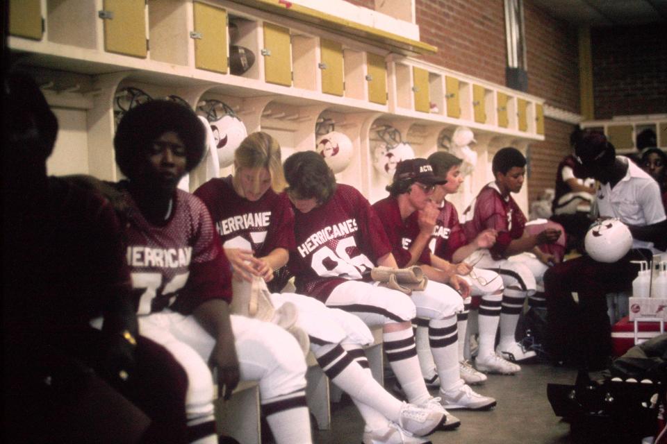 Members of the the Houston Herricanes in their locker room with coaches before one of their games