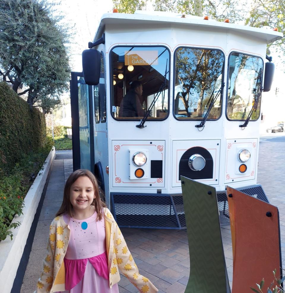 a girl in a peach dress standing in front of the garland trolley