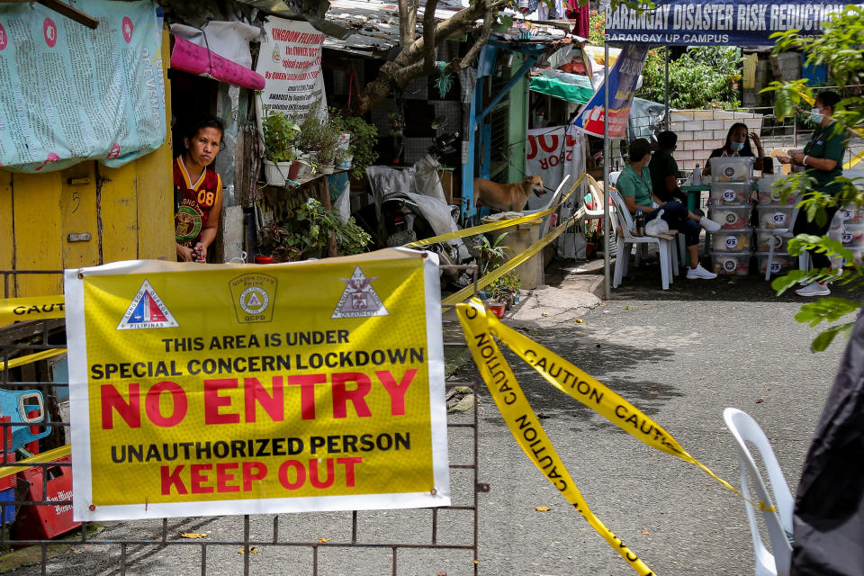 FILE PHOTO: A woman peeks through the door of her house as she waits for aid distribution inside a locked-down community in Quezon City, on August 6, 2021. (Photo: George Calvelo/NurPhoto via Getty Images)