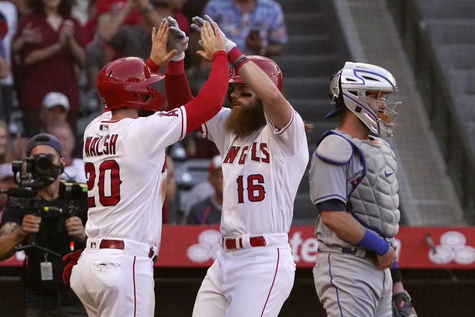 Los Angeles Angels' Brandon Marsh, center, is congratulated by Jared Walsh, left, after hitting a two-run home run as New York Mets catcher Tomas Nido stands at the plate during the second inning of a baseball game Friday, June 10, 2022, in Anaheim, Calif. (AP Photo/Mark J. Terrill)