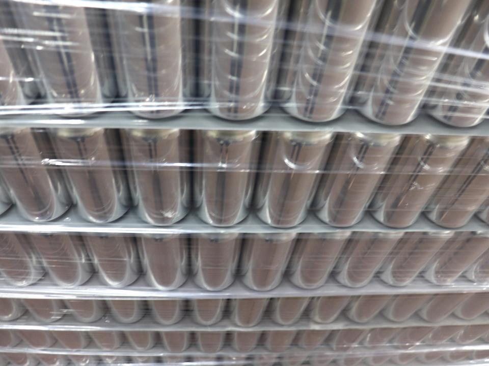 tall unlabeled shiny metal beer cans stacked in six layers and wrapped in plastic