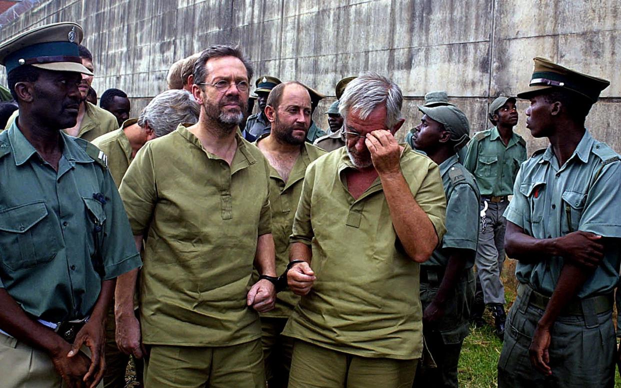 Simon Mann (left) in March 2004, leaving a court set up inside a maximum security prison in Harare, Zimbabwe, before being extradited to Equatorial Guinea - AFP