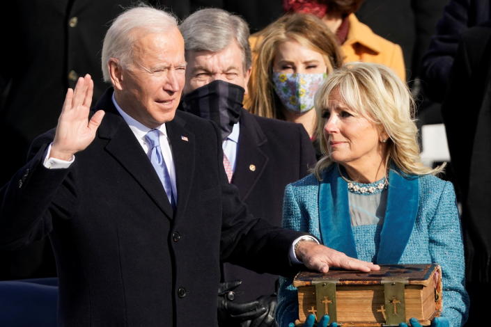 Joe Biden, with one hand on a Bible held by his wife and the other hand raised, is sworn in president.