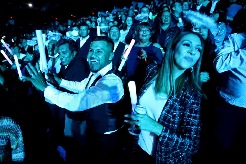 A man and woman dance together and smile during a concert.