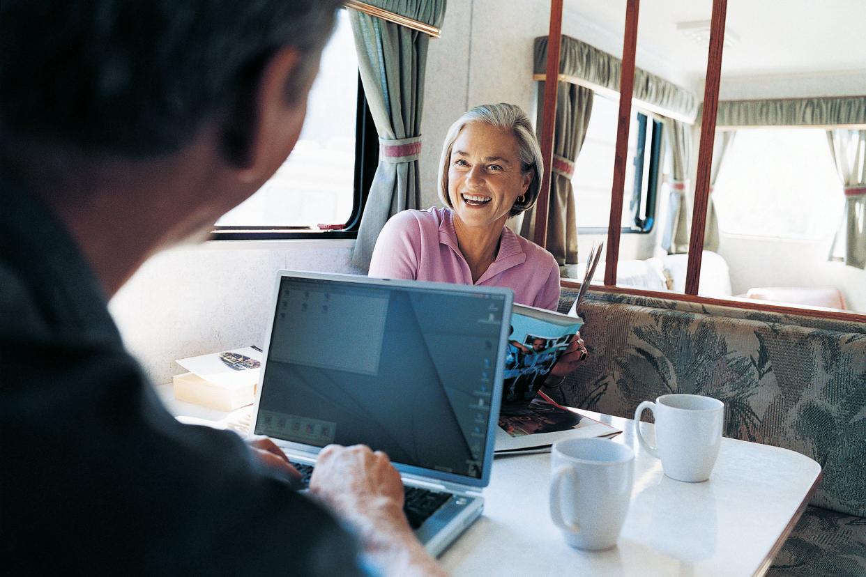 couple sitting at a table with their laptops in their motor home