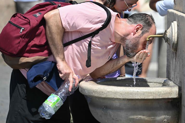 Un hombre bebe agua de una fuente mientras espera el Ángelus del Papa Francisco en el Vaticano el 9 de julio de 2023.