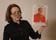 Anne Barrett Doyle, co-director of BishopAccountability.org group, holds up a photo of Cardinal Daniel DiNardo, the archbishop of Houston-Galveston and the president of the U.S. Conference of Catholic Bishops, during a press conference at the foreign press association in Rome, Tuesday Feb. 19, 2019. DiNardo has been accused by victims of downplaying their accusations against Rev. Manuel La Rosa-Lopez, who was charged in September with four counts of indecency with a child and has been criticized for allowing the Rev. John T. Keller, to celebrate Mass even though later in the day his name appeared on a list released by the church of credibly accused priests. (AP Photo/Alessandra Tarantino)