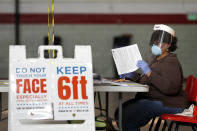 FILE - In this April 28, 2020, file photo, Louisa Boyer, a provisional election judge, reviews paperwork at a voting center at Edmondson High School as voters arrive to cast their ballot in the 7th Congressional District special election in Baltimore. As Republicans roll back access to the ballot, Democratic lawmakers have been quietly moving to expand voting rights. In Virginia, Maryland, Nevada and other states where Democrats have control, lawmakers are pushing to make it easier to cast ballots by mail, increase early voting and require greater oversight over changes to election law. (AP Photo/Julio Cortez, File)