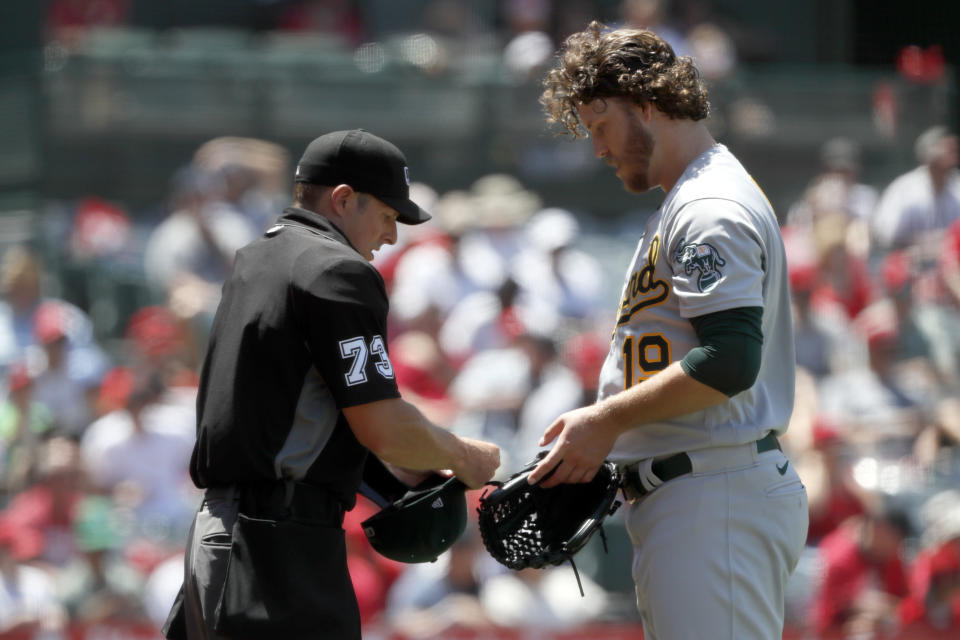 Home plate umpire Tripp Gibson, left, checks the equipment of Oakland Athletics starting pitcher Cole Irvin during the third inning of a baseball game against the Los Angeles Angels in Anaheim, Calif., Saturday, July 31, 2021. (AP Photo/Alex Gallardo)