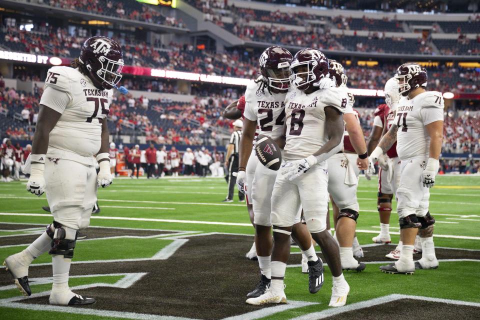 Sep 30, 2023; Arlington, Texas; Texas A&M Aggies offensive lineman Kam Dewberry (75) and running back Earnest Crownover (24) and running back Le'Veon Moss (8) celebrate during the second half against the Arkansas Razorbacks at AT&T Stadium. Jerome Miron-USA TODAY Sports