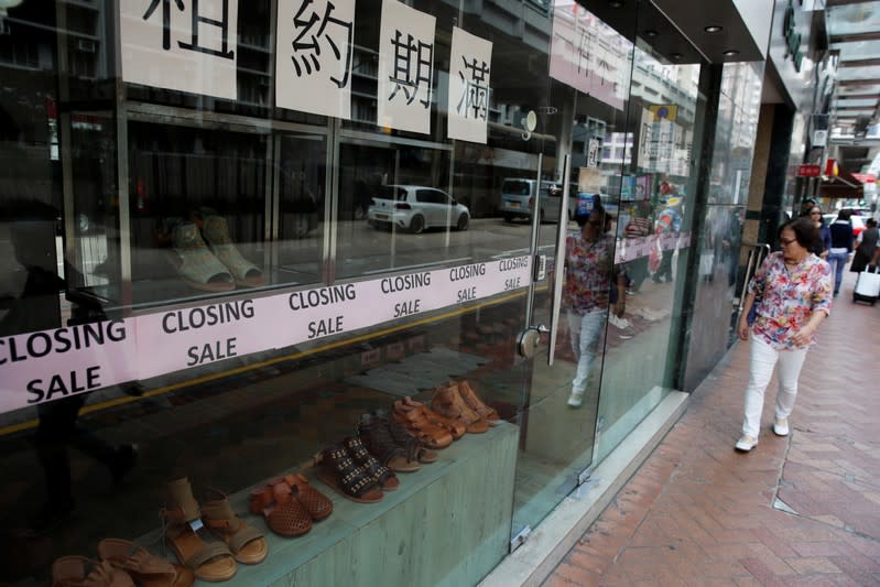 A woman walks past a shop with a closing sale in Hong Kong