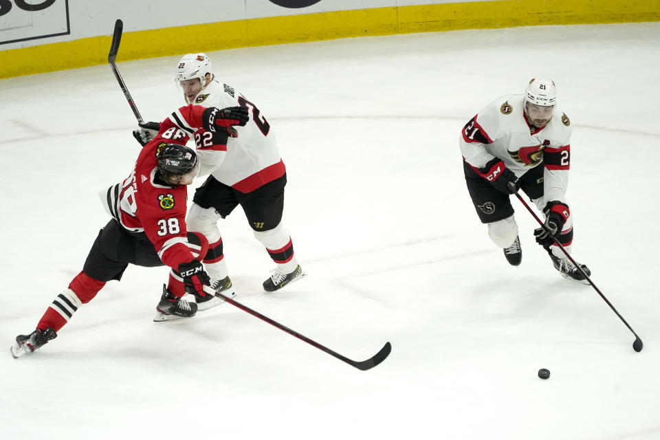 Ottawa Senators' Nikita Zaitsev (22) knocks Chicago Blackhawks' Brandon Hagel off his skates as Nick Paul advances the puck during the second period of an NHL hockey game Monday, Nov. 1, 2021, in Chicago. (AP Photo/Charles Rex Arbogast)