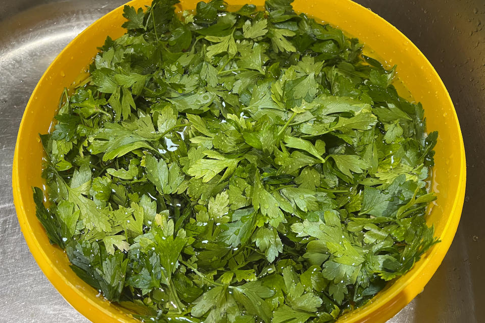 This 2023 image provided by Jessica Damiano shows parsely leaves in a bowl of water on Long Island, N.Y. All crops should be rinsed thoroughly before preserving, whether they will be canned, frozen or dried. (Jessica Damiano via AP)