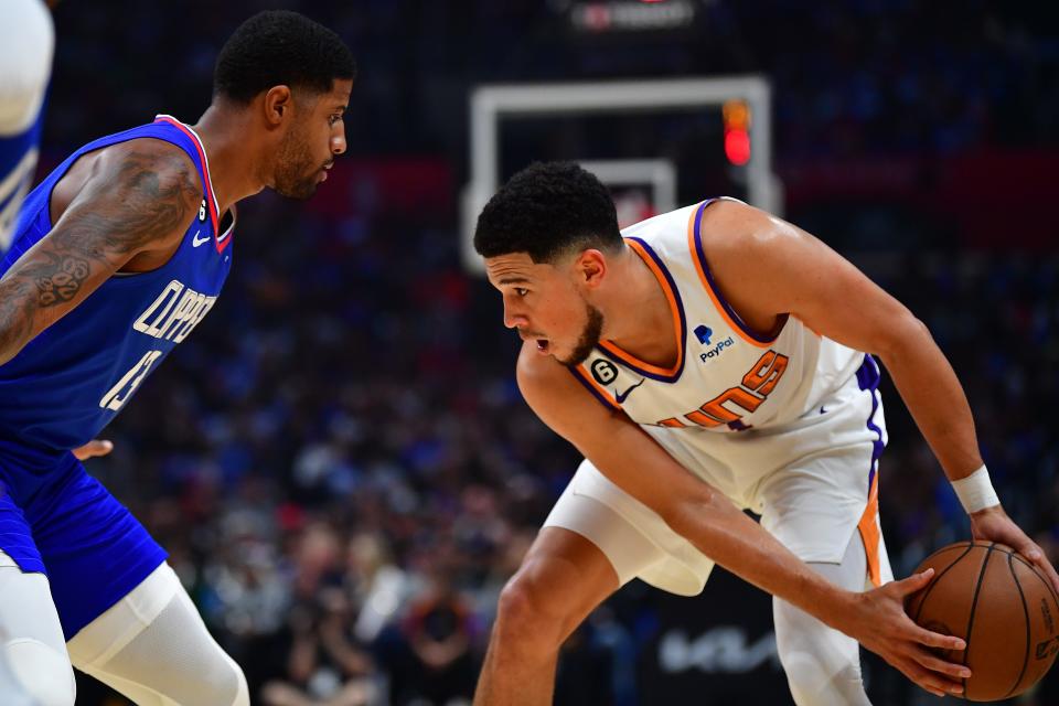 Phoenix Suns guard Devin Booker (1) moves the ball against Los Angeles Clippers guard Paul George (13) during the first half at Crypto.com Arena in Los Angeles on Oct. 23, 2022.