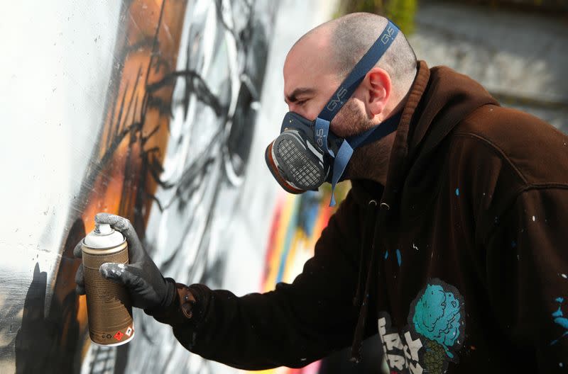 Artist Perez paints a graffiti of a cashier to pay tribute to essential workers in Gland