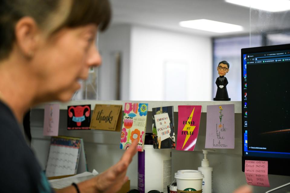 A person sits talking at a desk. A figurine of Justice Ruth Bader Ginsberg is visible.