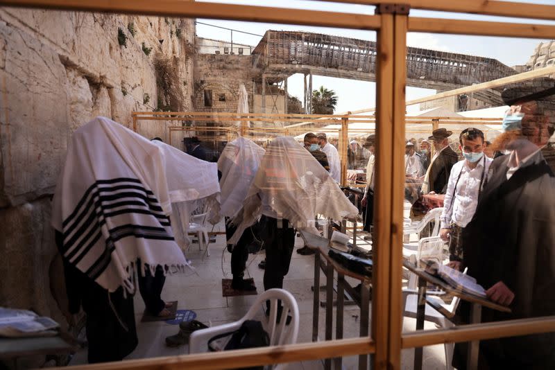 Ultra-Orthodox Jewish men, some covered in prayer shawls, are seen through a part of a partitioned area, placed for worshippers to adhere to COVID-19 restrictions, as they pray in front of the Western Wall, in Jerusalem's Old City