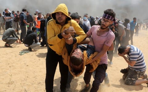 Palestinians carry a protestor injured near the Gaza-Israel border at Rafah - Credit: Rahim Khatib/Anadolu Agency