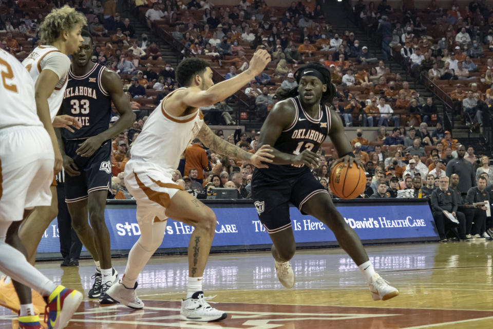 Oklahoma State guard Issac Likekele, right, drives the ball against Texas forward Timmy Allen, left, during the first half of an NCAA college basketball game, Saturday, Jan. 22, 2022, in Austin, Texas. (AP Photo/Michael Thomas)