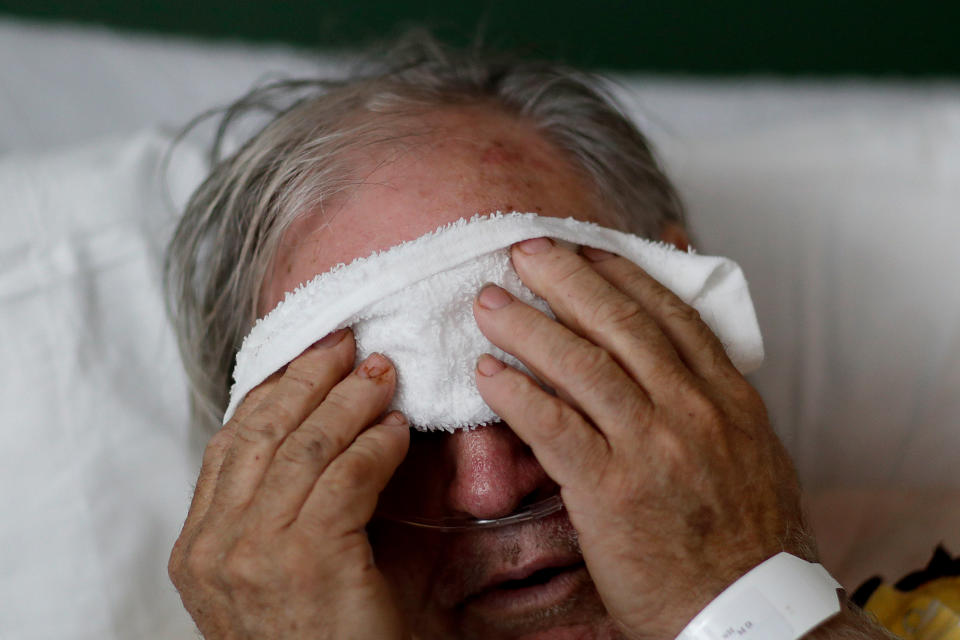 FILE - In this Friday, Feb. 9, 2018 file photo, a 73-year-old man places a cold compress on his forehead while battling the flu at a hospital in Georgia. Doctors can test for the flu and get results within a day, but coronavirus testing as of March 2020 is still limited in the United States by availability. (AP Photo/David Goldman)