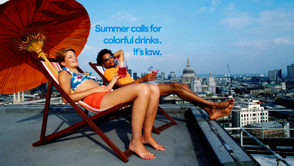 a couple of women sitting on a chair on a deck with a city in the background