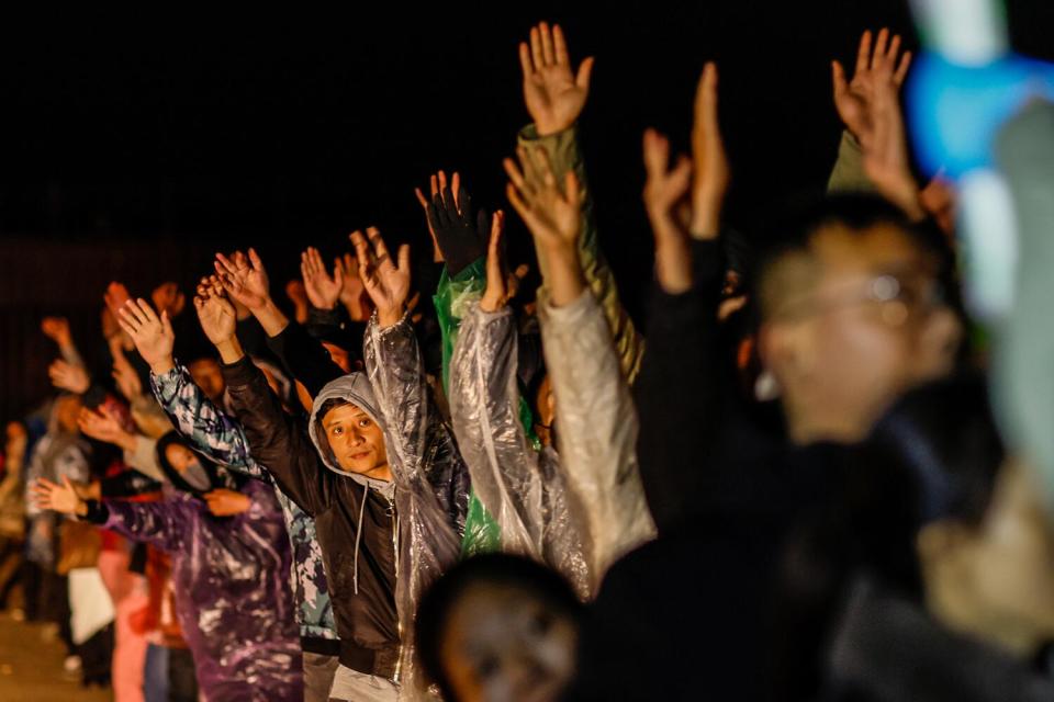 Migrantes hacen cola ansiosamente frente a un agente de la Patrulla Fronteriza.