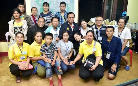 Thailand's Prime Minister Prayuth Chan-ocha poses with relatives of boys trapped in a flooded cave at the Tham Luang cave complex in Chiang Rai - Credit: REUTERS 