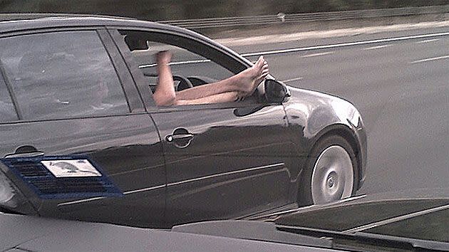 A driver heading down the Eastern Freeway with his feet hanging out the window.