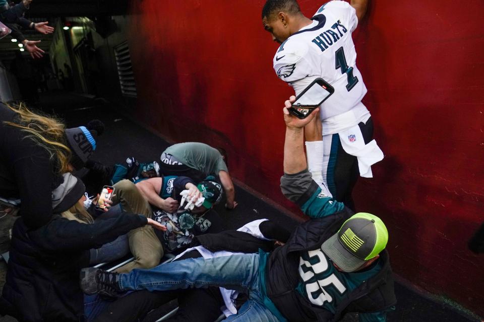 Fans hit the ground in front of Eagles quarterback Jalen Hurts (1) after a railing collapsed following the end of the Eagles-WFT game on Sunday.