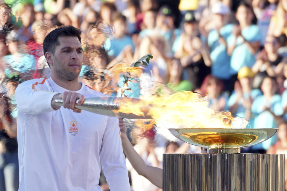 Greek Olympic medalist Ioannis Fountoulis lights the caldron with the Olympic Flame during the Olympic flame handover ceremony at Panathenaic stadium, where the first modern games were held in 1896, in Athens, Friday, April 26, 2024. On Saturday the flame will board the Belem, a French three-masted sailing ship, built in 1896, to be transported to France. (AP Photo/Petros Giannakouris)