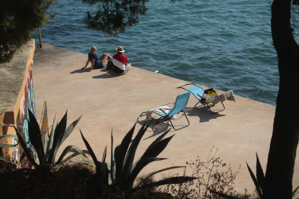 Sunbathers enjoy the beach in Palma de Mallorca, Spain, Sunday, July 26, 2020. Britain has put Spain back on its unsafe list and announced Saturday that travelers arriving in the U.K. from Spain must now quarantine for 14 days. The move by the UK taken without forewarning has caught travelers off guard. (AP Photo/Joan Mateu)