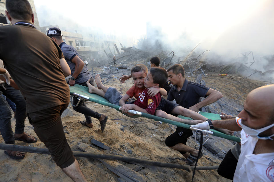 Palestinians evacuate two wounded boys out of the destruction following Israeli airstrikes on Gaza City, Wednesday, Oct. 25, 2023. Hundreds of thousands of Palestinians have decided to stay in their homes in northern Gaza despite Israeli warnings that they are facing grave danger if they don't move to an evacuation zone in the southern part of the territory. (AP Photo/Abed Khaled)