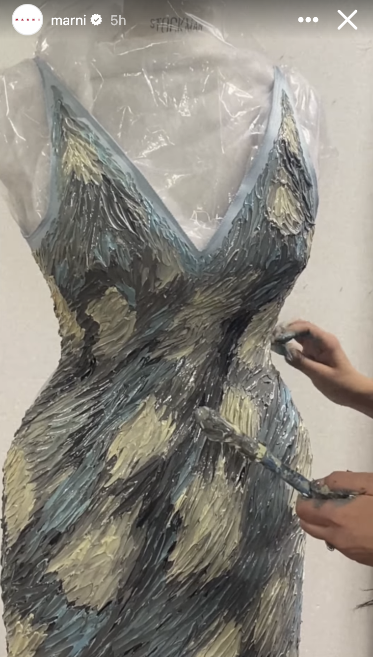 Person painting a detailed pattern on a dress being designed. No faces shown