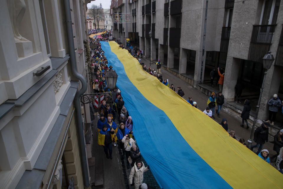 FILE - People carry a giant Ukrainian flag to mark the first anniversary of Russia's full-scale invasion of Ukraine, in Vilnius, Lithuania, Friday, Feb. 24, 2023. Former Lithuanian President Dalia Grybauskaite has said that many Europeans still fail to understand the chasm in values between Russia and the West. She dismissed as "delusions" the idea that the two sides could find common ground through negotiations. (AP Photo/Mindaugas Kulbis, File)