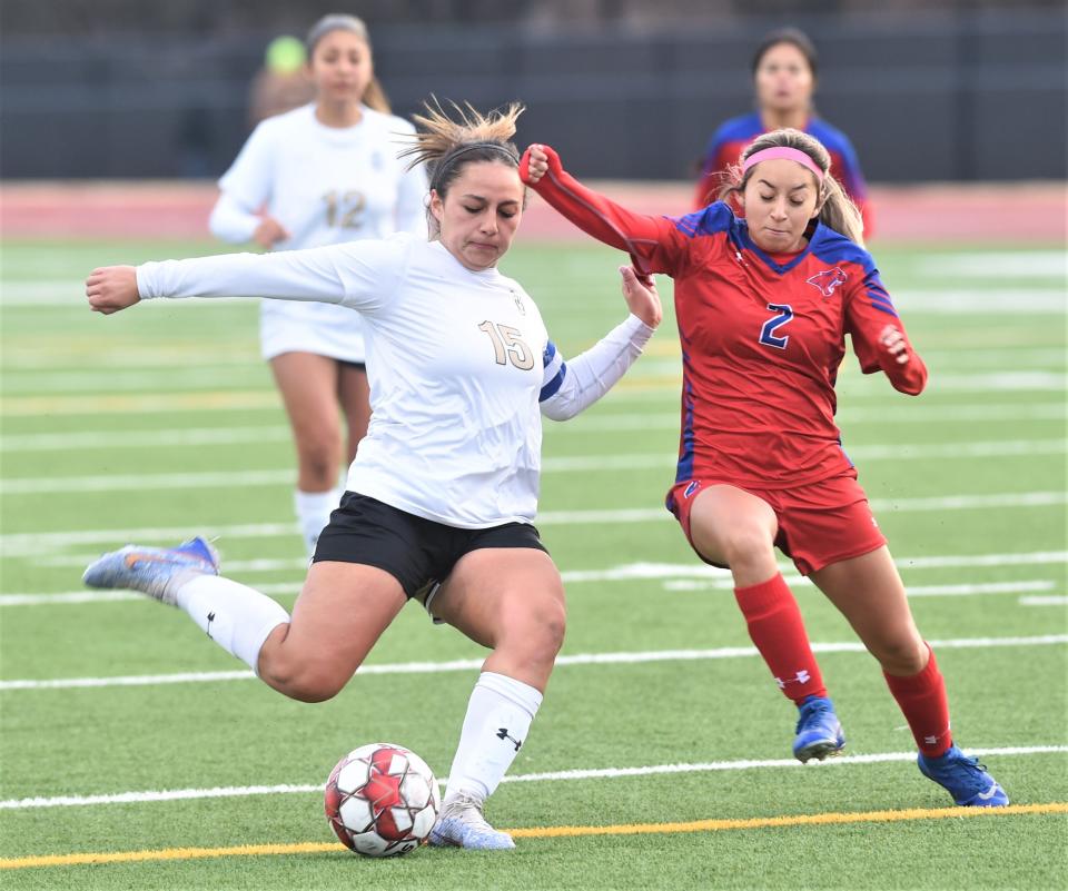 Abilene High's Justine Martinez, left, prepares to kick the ball as Cooper's Yesenia Rodriguez defends in the first half.