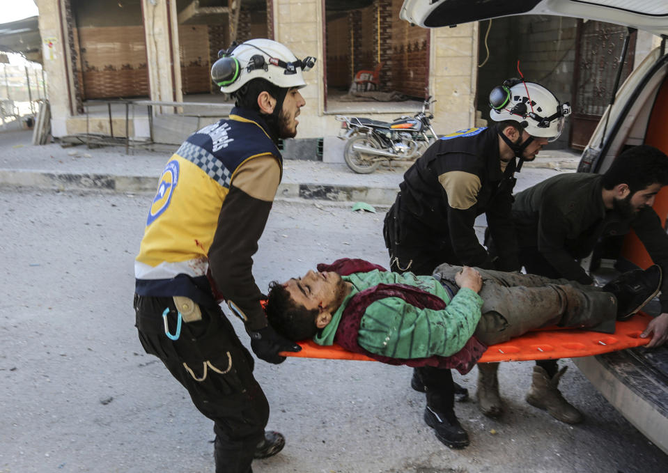 This photo released Tuesday, Feb. 19, 2019, by the Syrian Civil Defense group known as the White Helmets, shows Syrian White Helmet civil defense workers carrying an injured man who was wounded by a shell from Syrian forces, in the town of Khan Sheikhoun, Idlib, north Syria. The Britain-based Syrian Observatory for Human Rights said the shelling on the town of Khan Sheikhoun hit the main bakery that supplies the town and nearby villages with bread. It said several people were killed in the shelling including children. (Syrian Civil Defense White Helmets via AP)