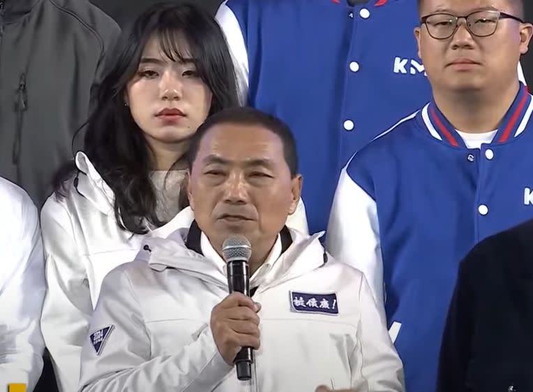 國民黨發言人楊智伃站在侯友宜後方，聽敗選宣言難過落淚。（鏡新聞）