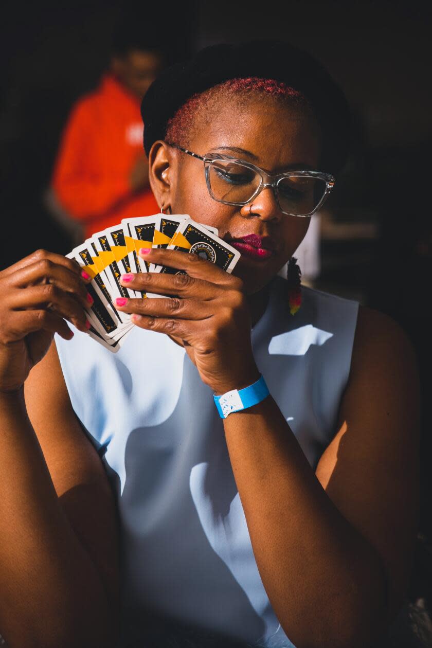 A person holds a card hand fanned in front of her face