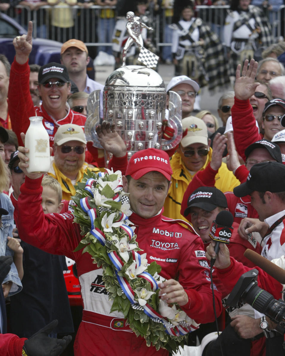 FILE - Gil de Ferran, of Brazil, holds up the winner's bottle of milk in Victory Circle after his win in the Indianapolis 500 auto race May 25, 2003, in Indianapolis. De Ferran, holder of the closed-course land speed record, died Friday, Dec. 29, 2023, while racing with his son at The Concourse Club in Florida, multiple former colleagues confirmed to The Associated Press. He was 56. (AP Photo/Michael Conroy, File)