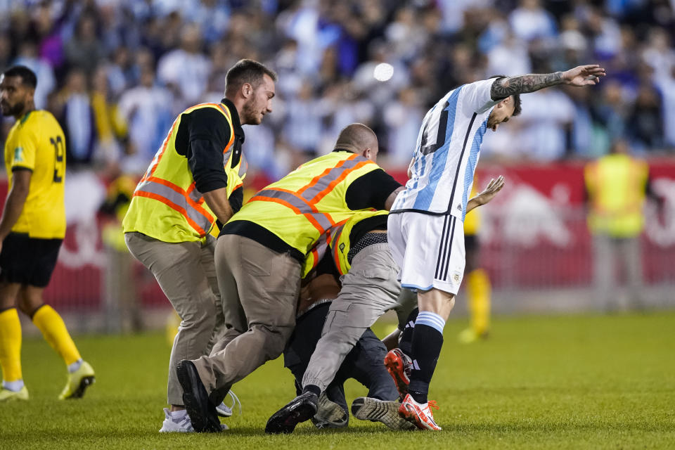 A fan is tackled as he tries to take a selfie with Argentina's player Lionel Messi as he celebrates his goal during the second half of an international friendly soccer match against Jamaica on Tuesday, Sept. 27, 2022, in Harrison, N.J. (AP Photo/Eduardo Munoz Alvarez)