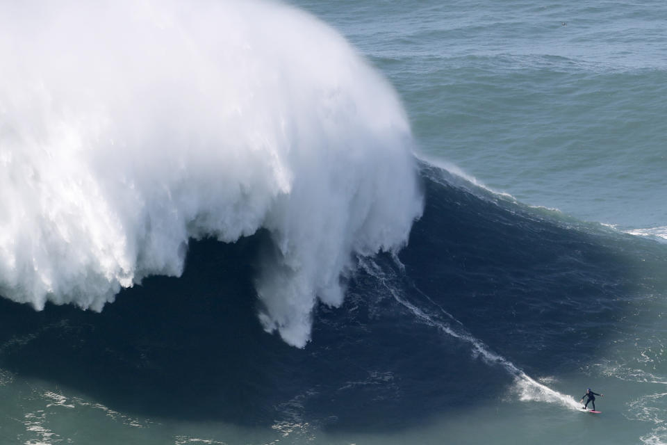 A surfer rides a wave during a tow surfing session at Praia do Norte or North Beach in Nazare, Portugal, Thursday, Oct. 29, 2020. A big swell generated earlier in the week by Hurricane Epsilon in the North Atlantic, reached the Portuguese west coast drawing big wave surfers to Nazare. (AP Photo/Pedro Rocha)